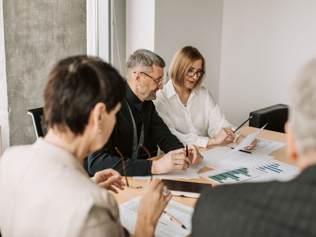 Equipe conferindo documentos e planilhas de custo sobre a mesa