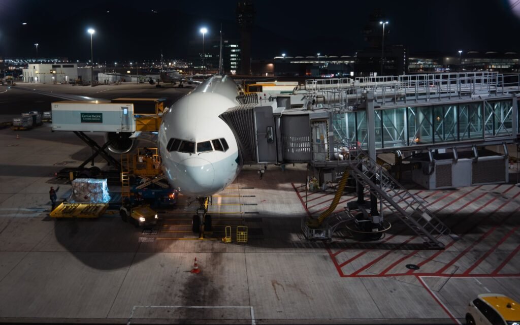 Avião no pátio do aeroporto à noite, com carga paletizada sendo levada ao porão