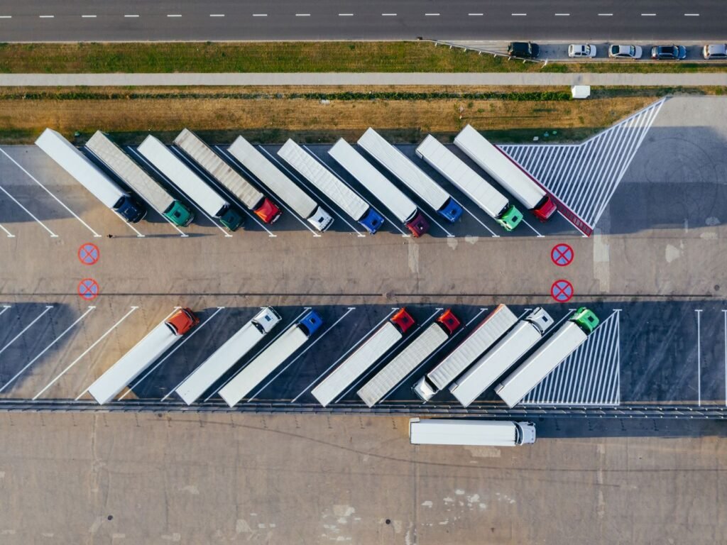 Vista aérea de caminhões de carga estacionados em fileiras num pátio de transportadora